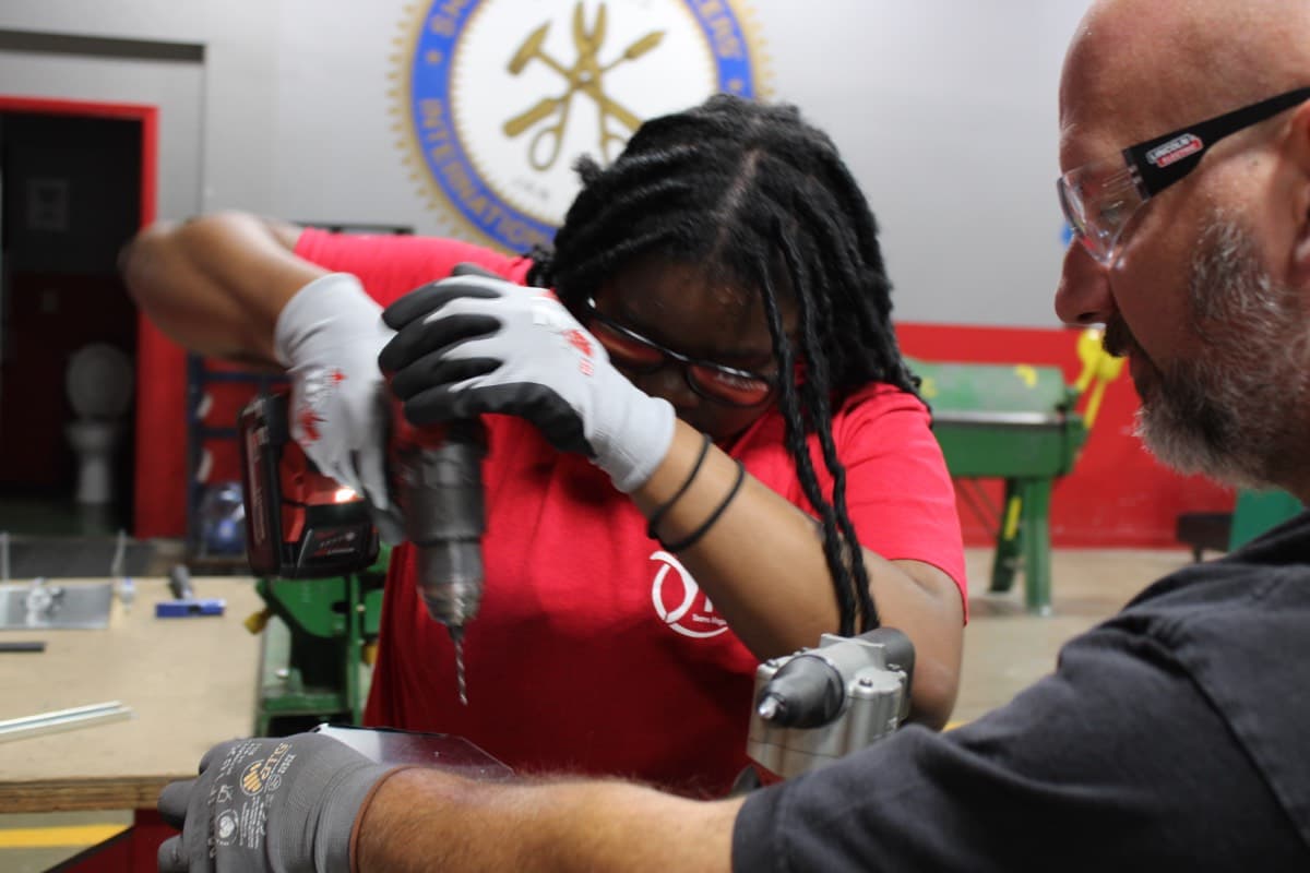 Youth learning to use a power drill with a mentor